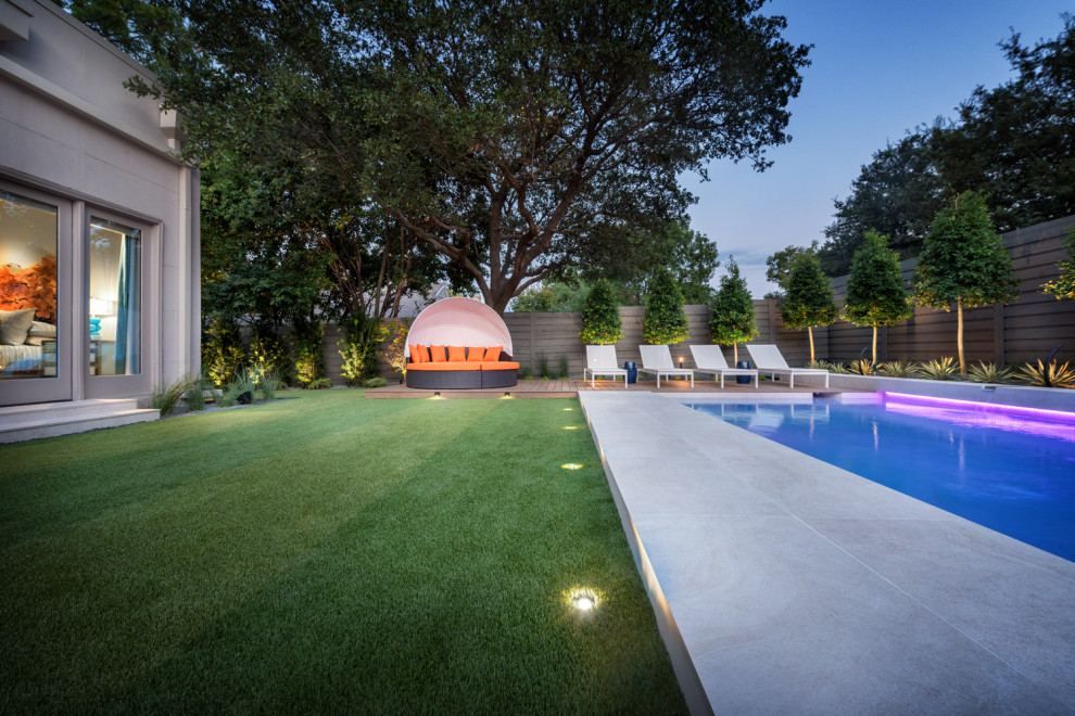 На фото: большой прямоугольный ландшафтный бассейн на заднем дворе в стиле модернизм с покрытием из каменной брусчатки с