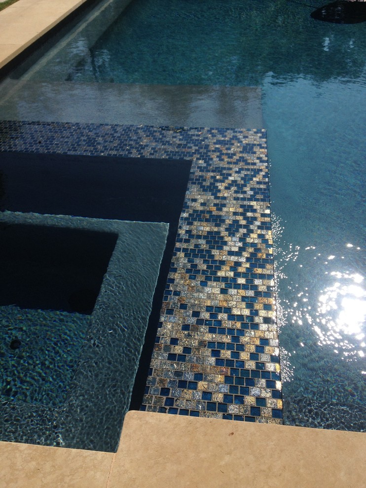 Imagen de casa de la piscina y piscina alargada actual grande en forma de L en patio trasero con losas de hormigón