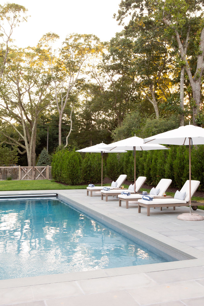 Imagen de piscina con fuente alargada costera grande rectangular en patio trasero con adoquines de hormigón