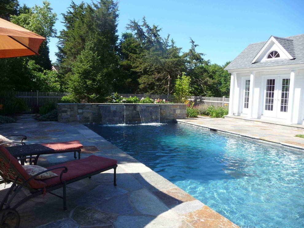 Imagen de piscina con fuente alargada tradicional rectangular en patio trasero con adoquines de piedra natural