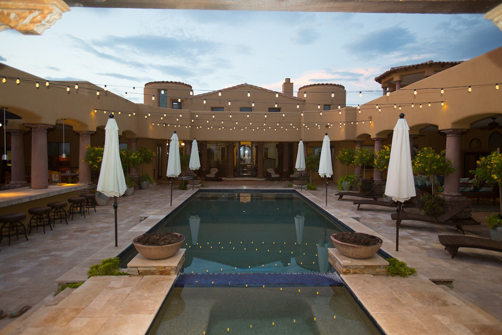 This is an example of an expansive bohemian back rectangular hot tub in Phoenix with natural stone paving.