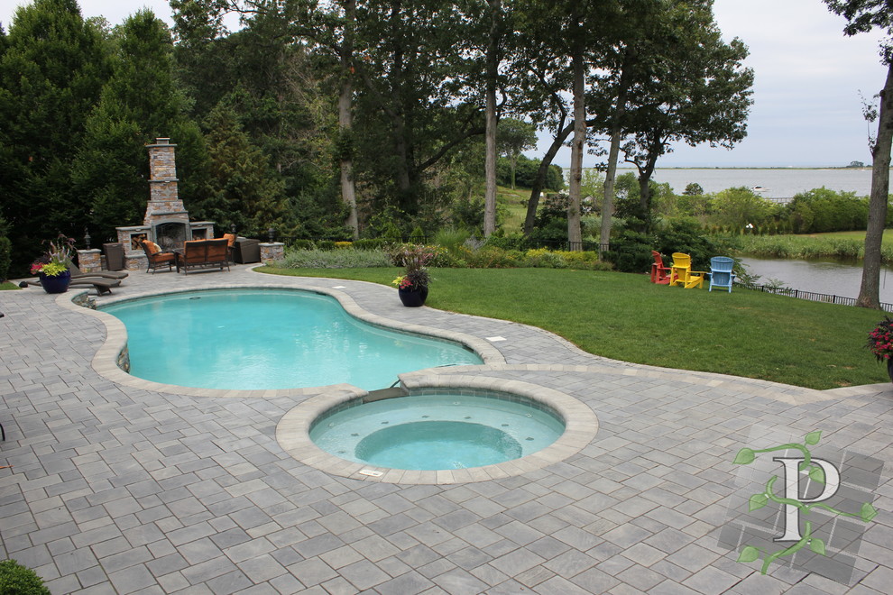 Photo of a large traditional back custom shaped hot tub in New York with concrete paving.