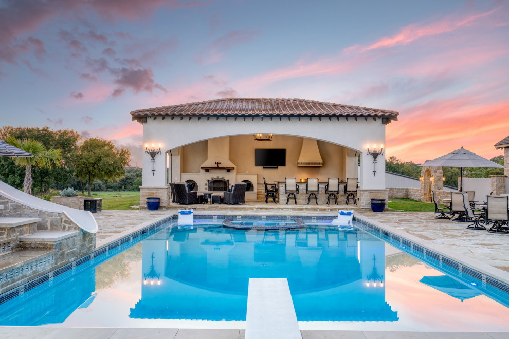 На фото: большой прямоугольный бассейн на заднем дворе в средиземноморском стиле с домиком у бассейна и покрытием из каменной брусчатки с
