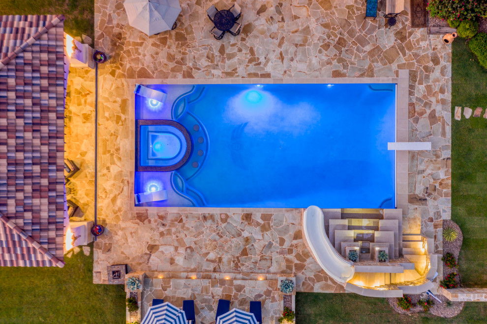 Ispirazione per una grande piscina mediterranea rettangolare dietro casa con una dépendance a bordo piscina e pavimentazioni in pietra naturale