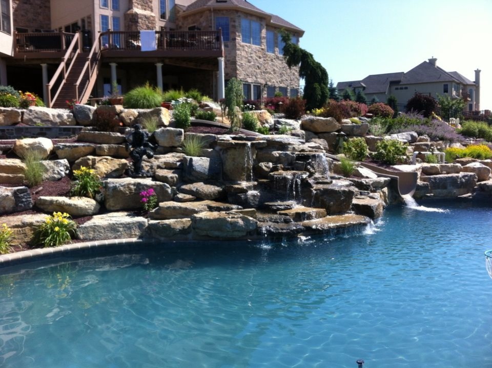 Idee per una piscina naturale chic personalizzata dietro casa con un acquascivolo e pavimentazioni in mattoni
