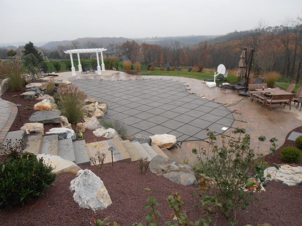 Ispirazione per una piscina naturale tradizionale personalizzata dietro casa con un acquascivolo e pavimentazioni in mattoni