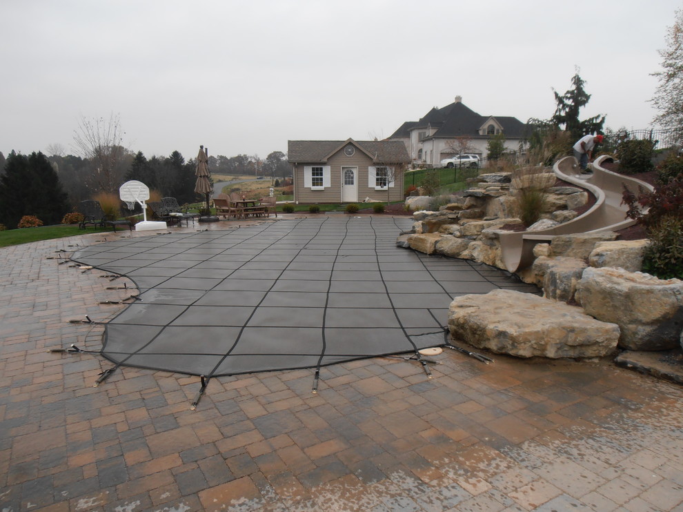 Idee per una piscina naturale classica personalizzata dietro casa con un acquascivolo e pavimentazioni in mattoni