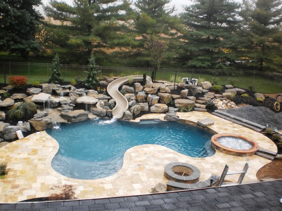 Imagen de piscina con tobogán natural clásica grande a medida en patio trasero con adoquines de piedra natural