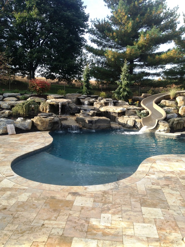 Modelo de piscina con tobogán natural tradicional grande a medida en patio trasero con adoquines de piedra natural