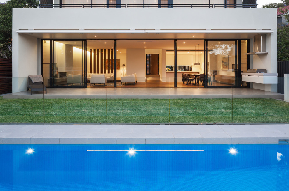 Ejemplo de piscina alargada minimalista de tamaño medio rectangular en patio trasero con suelo de baldosas
