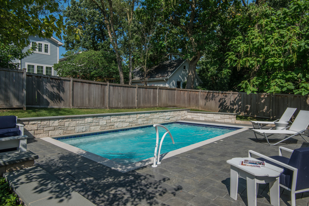 Ejemplo de piscina alargada tradicional pequeña rectangular en patio trasero con adoquines de hormigón
