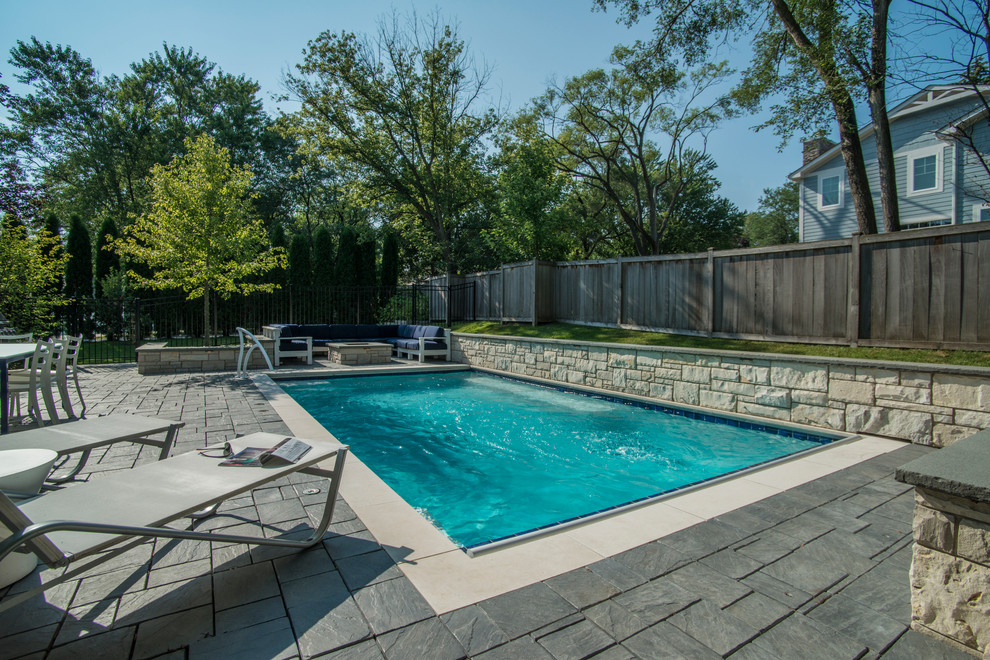 Diseño de piscina alargada clásica pequeña rectangular en patio trasero con adoquines de hormigón