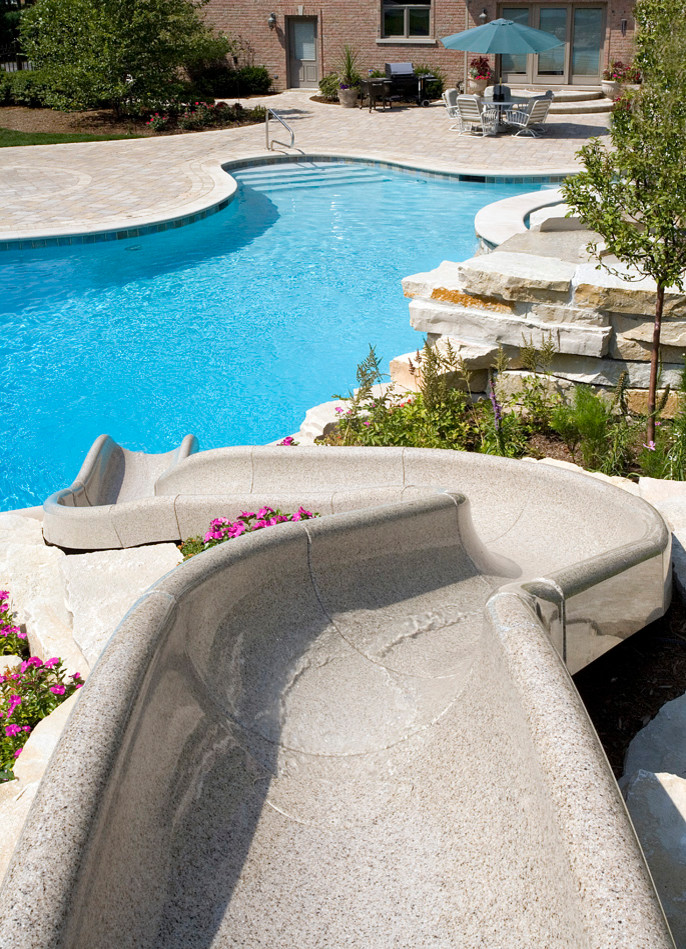 Foto de piscina con tobogán natural rústica extra grande a medida en patio trasero con adoquines de hormigón