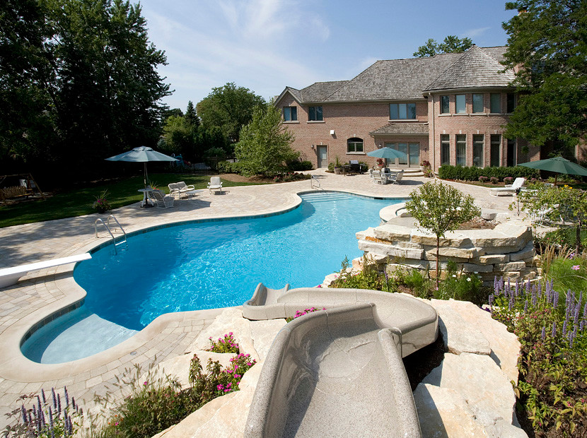 Imagen de piscina con tobogán natural rústica extra grande a medida en patio trasero con adoquines de hormigón