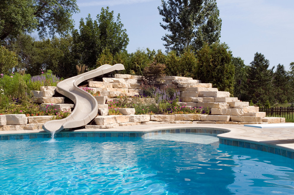 Ejemplo de piscina con tobogán natural rústica extra grande a medida en patio trasero con adoquines de hormigón