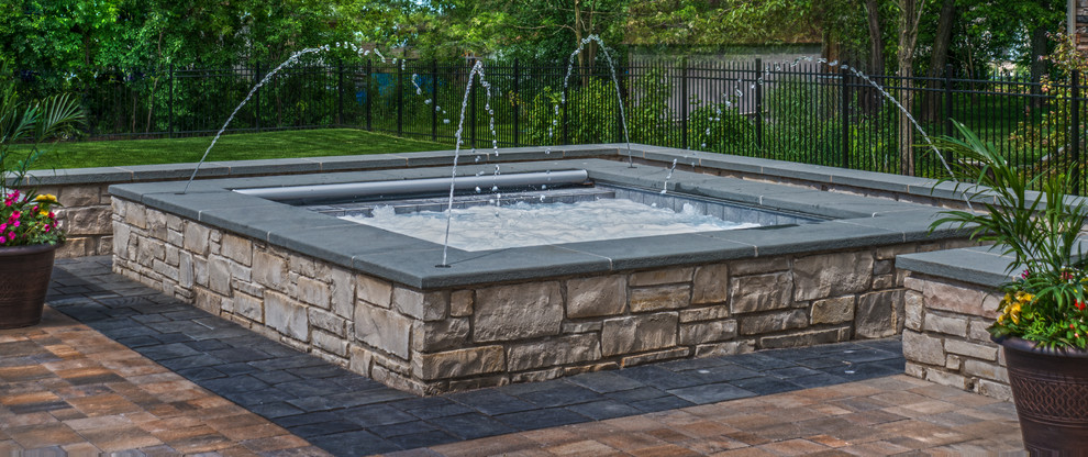 Photo of a small classic back rectangular natural hot tub in Chicago with concrete paving.