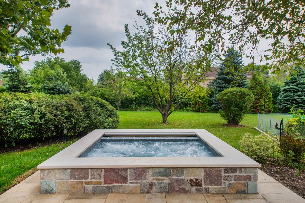 Immagine di una piccola piscina naturale rustica rettangolare dietro casa con una vasca idromassaggio e pavimentazioni in pietra naturale