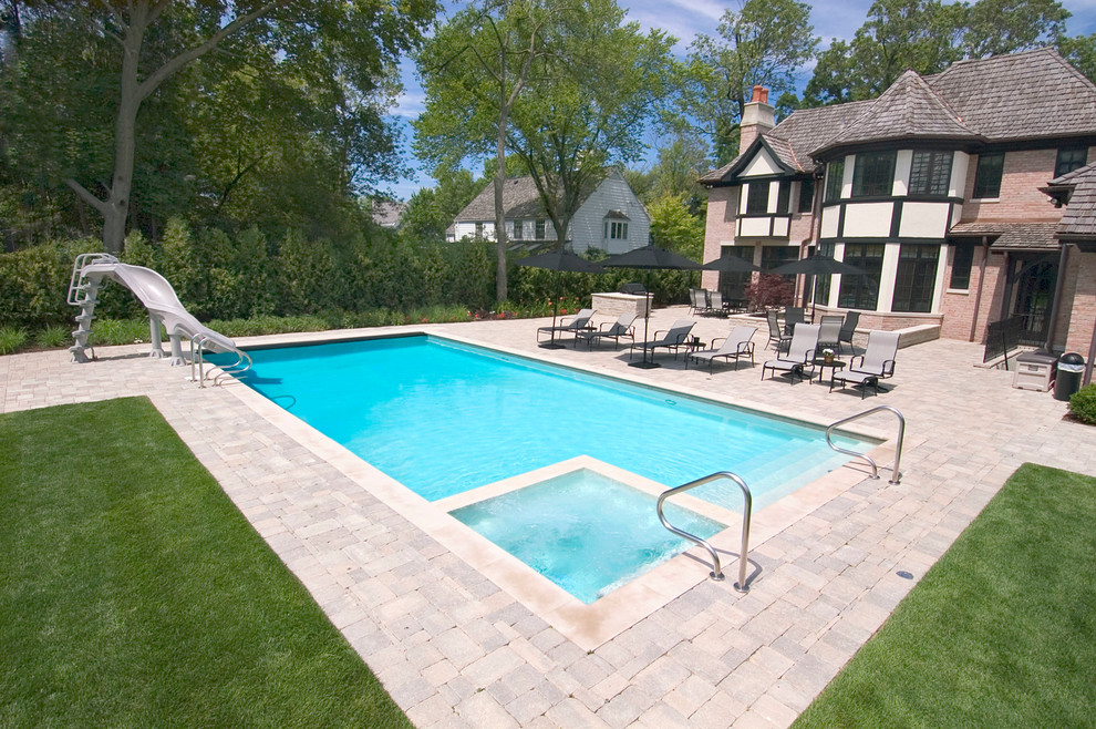 Foto de piscinas y jacuzzis alargados clásicos de tamaño medio rectangulares en patio trasero con adoquines de hormigón