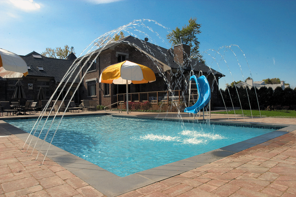Imagen de piscinas y jacuzzis alargados tradicionales de tamaño medio rectangulares en patio trasero con adoquines de hormigón