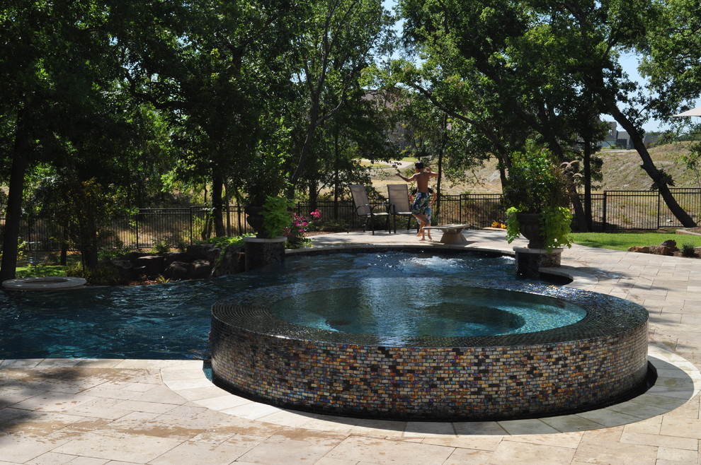 Photo of a large bohemian back custom shaped swimming pool in Dallas with natural stone paving.