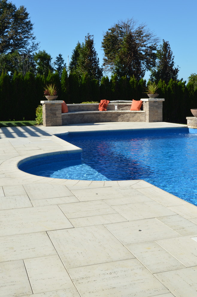 Imagen de piscina costera a medida en patio trasero con adoquines de hormigón