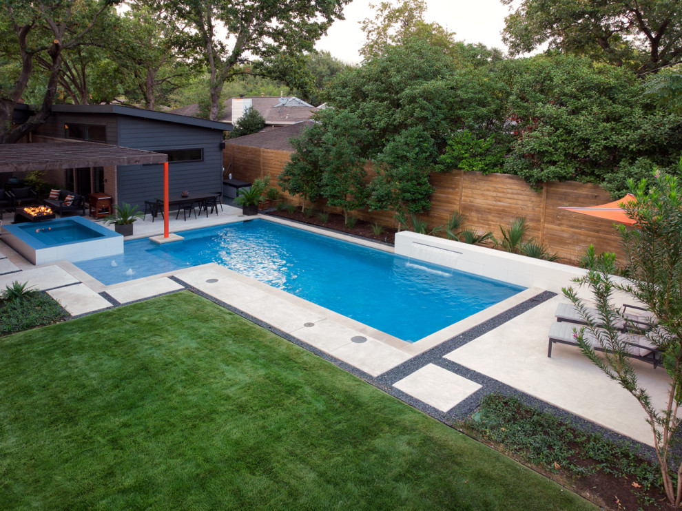 На фото: угловой бассейн среднего размера на заднем дворе в стиле модернизм с фонтаном и покрытием из бетонных плит
