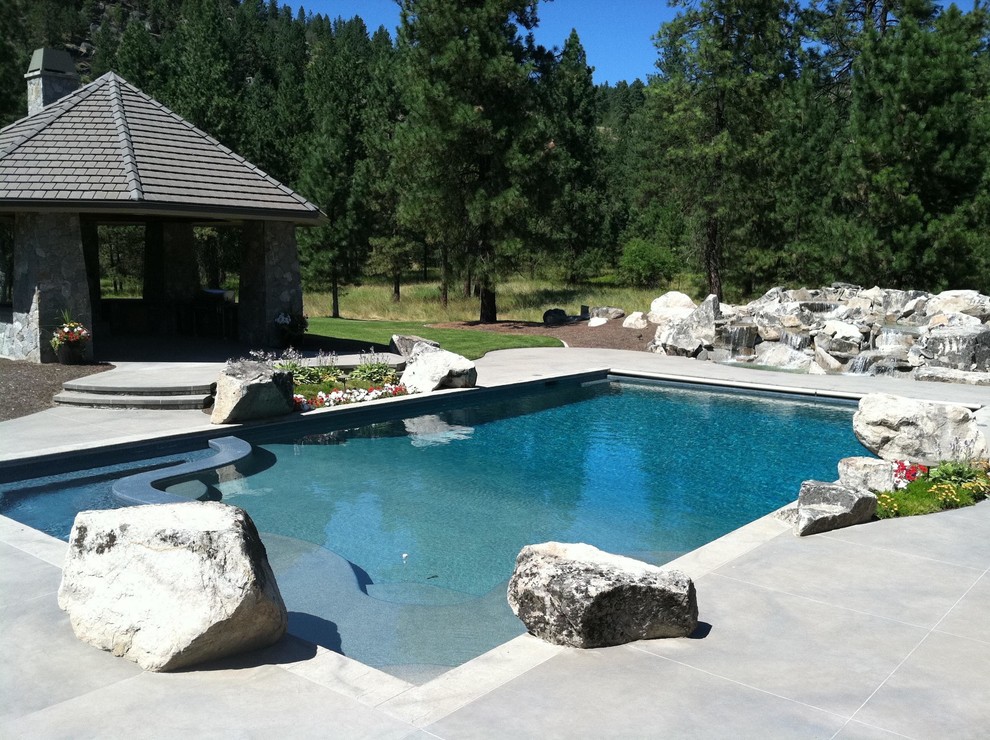Modelo de piscina con fuente actual grande rectangular en patio trasero con suelo de hormigón estampado