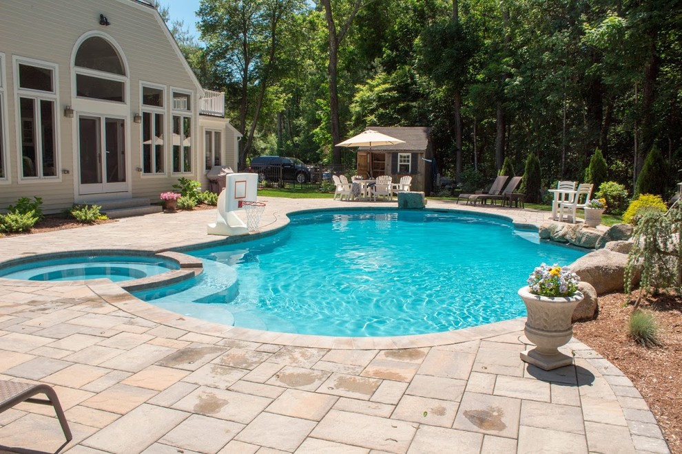 Idee per un'ampia piscina naturale tropicale a "C" dietro casa con una vasca idromassaggio e pavimentazioni in pietra naturale