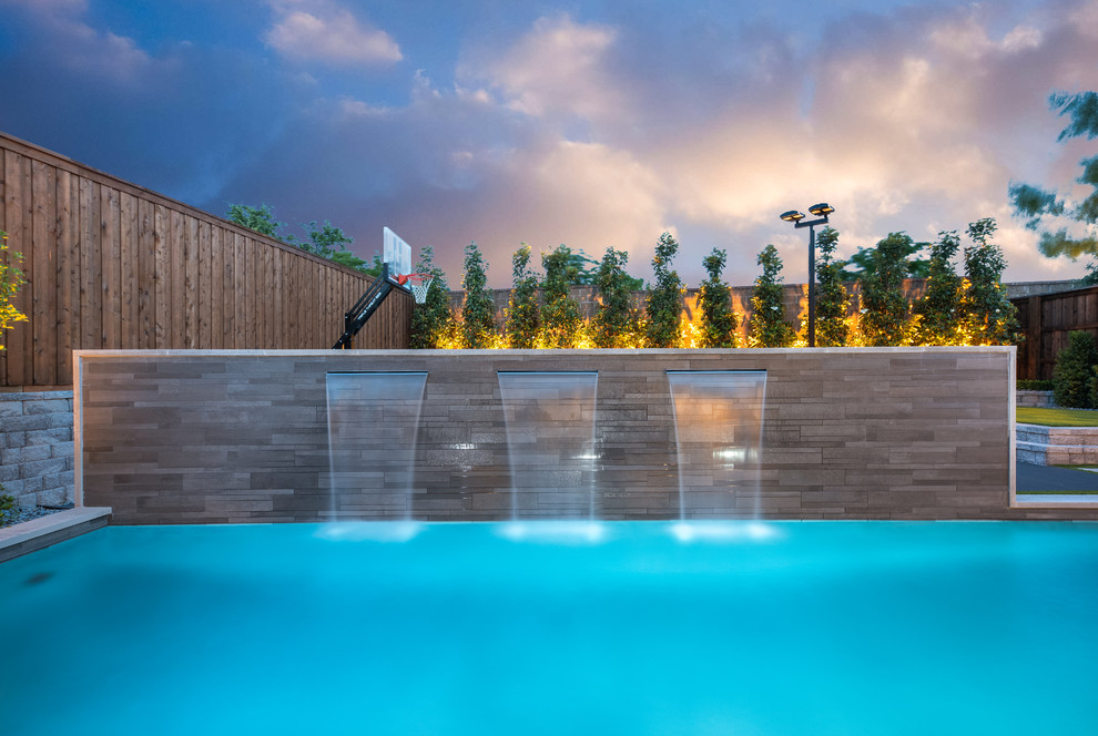 Photo of a modern rectangular swimming pool in Dallas with concrete slabs.