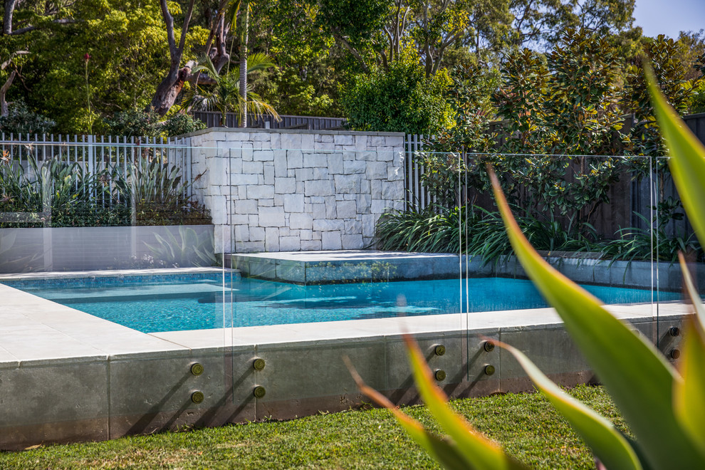На фото: угловой, спортивный бассейн среднего размера на заднем дворе в современном стиле с покрытием из каменной брусчатки и домиком у бассейна с