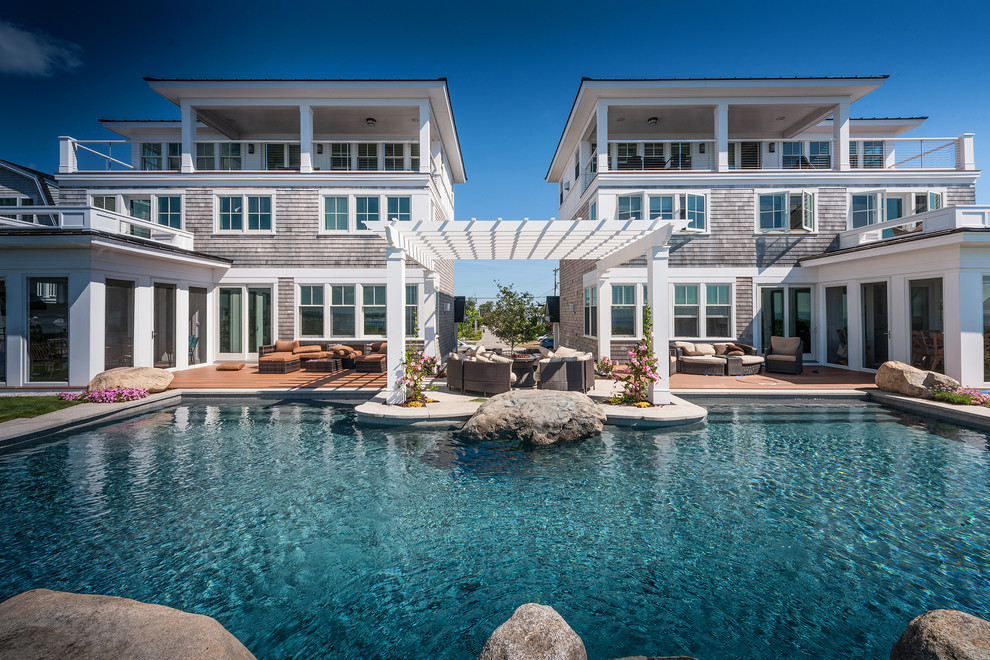 Immagine di una grande piscina monocorsia stile marinaro personalizzata dietro casa con fontane e lastre di cemento