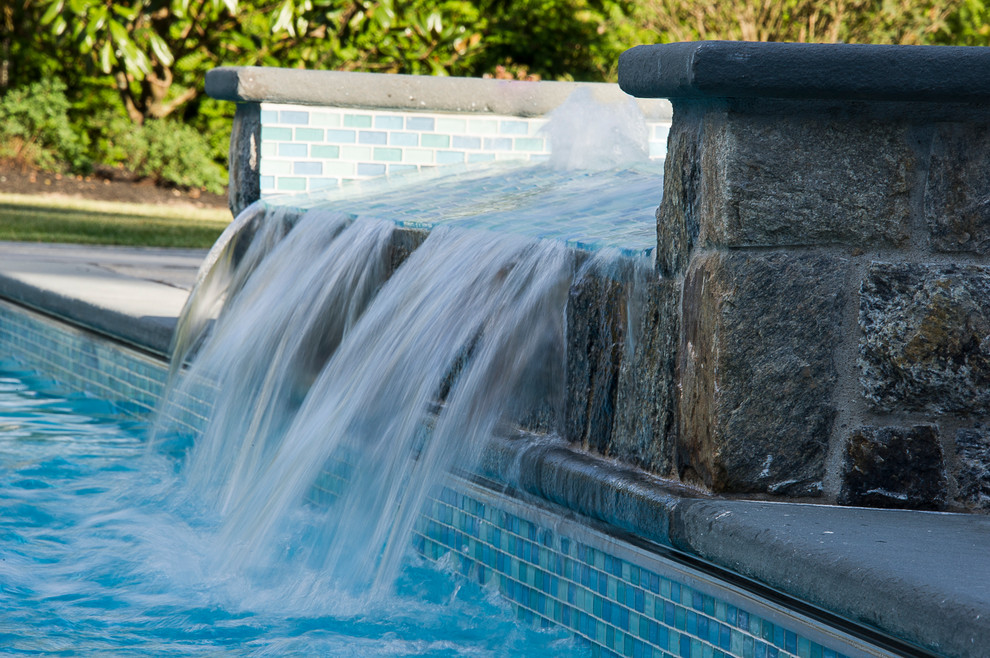Aménagement d'une piscine naturelle et arrière classique rectangle avec un bain bouillonnant et des pavés en pierre naturelle.