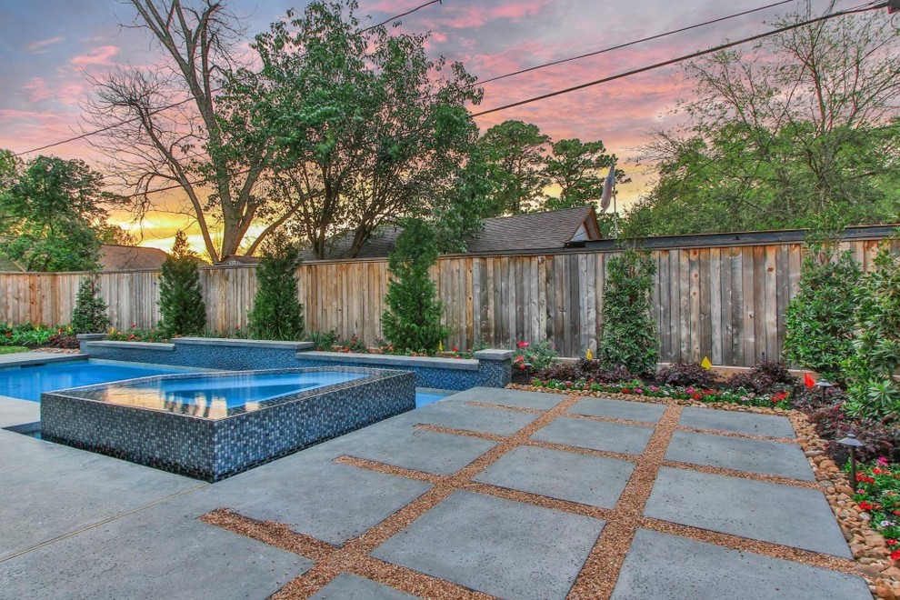 Esempio di una piscina naturale chic rettangolare di medie dimensioni e dietro casa con una vasca idromassaggio e pavimentazioni in cemento