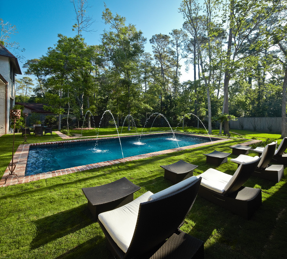 Diseño de piscina con fuente clásica rectangular en patio trasero con adoquines de ladrillo