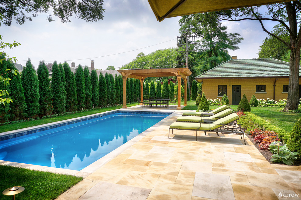 На фото: прямоугольный бассейн среднего размера на заднем дворе в викторианском стиле с домиком у бассейна и покрытием из каменной брусчатки