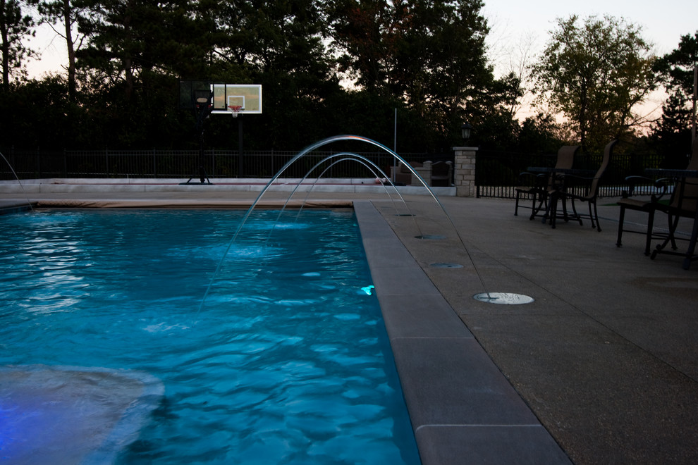 Ispirazione per una piscina tradizionale rettangolare di medie dimensioni e dietro casa con fontane e lastre di cemento