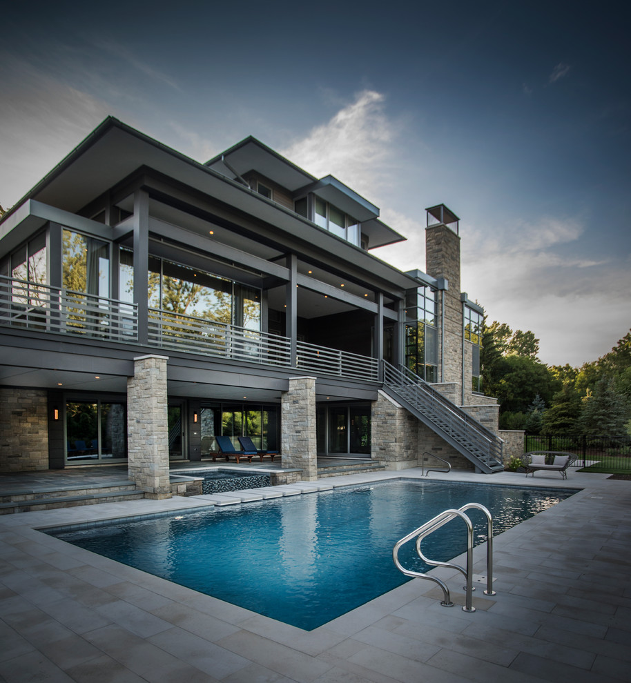 Ispirazione per una piscina a sfioro infinito minimal rettangolare di medie dimensioni e dietro casa con una vasca idromassaggio e pavimentazioni in pietra naturale
