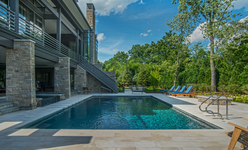 Modelo de piscinas y jacuzzis infinitos actuales de tamaño medio rectangulares en patio trasero con adoquines de piedra natural