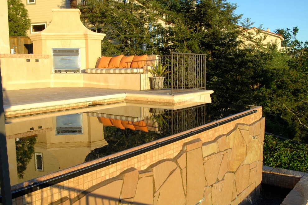 Modern inredning av en mellanstor rektangulär infinitypool på baksidan av huset, med stämplad betong