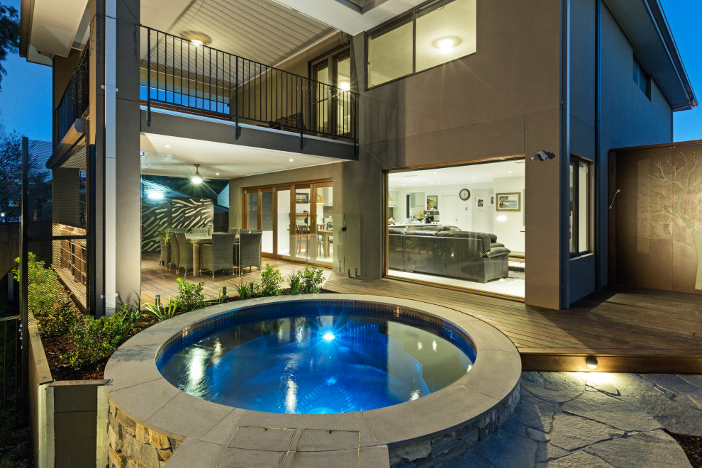 Idée de décoration pour un grand couloir de nage arrière minimaliste rond avec un bain bouillonnant et une terrasse en bois.