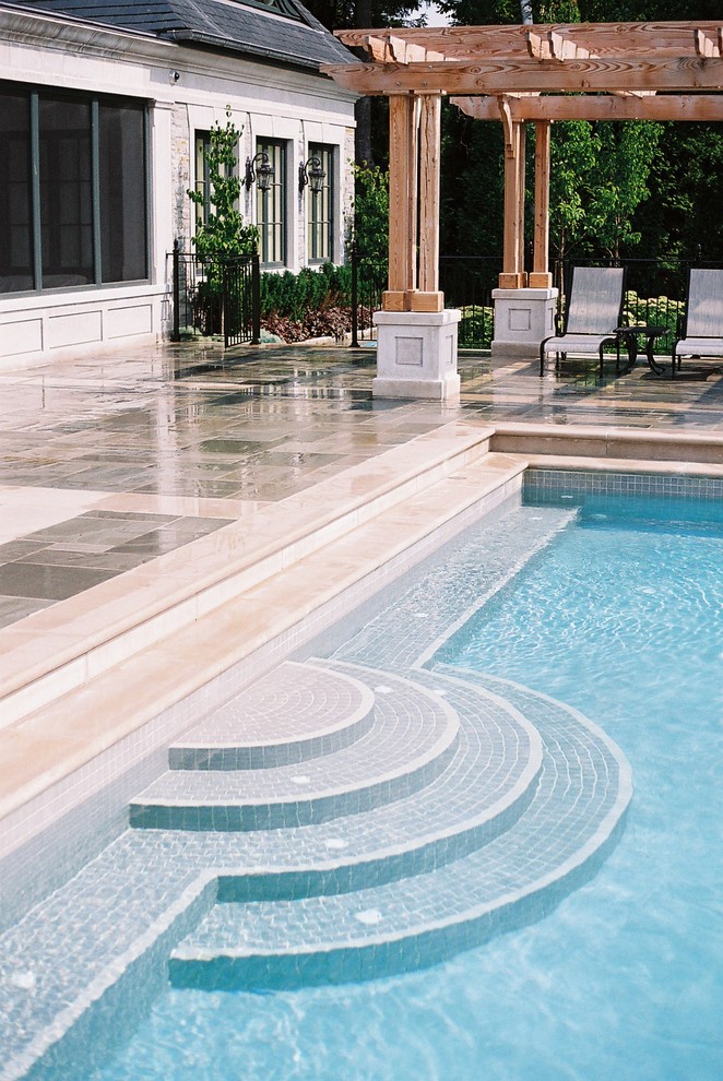 Medium sized traditional back rectangular infinity swimming pool in Toronto with a water feature and concrete paving.