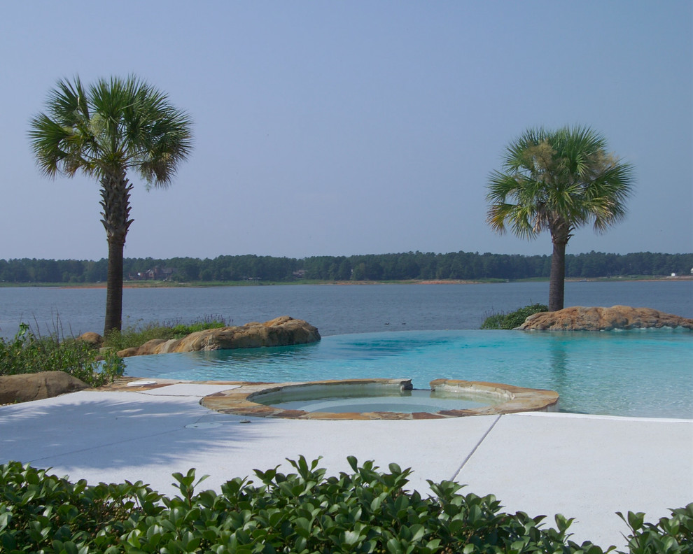 Idee per una grande piscina naturale stile marino personalizzata dietro casa con una vasca idromassaggio e lastre di cemento