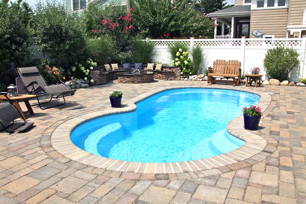 Foto de piscina alargada clásica tipo riñón en patio trasero con adoquines de hormigón