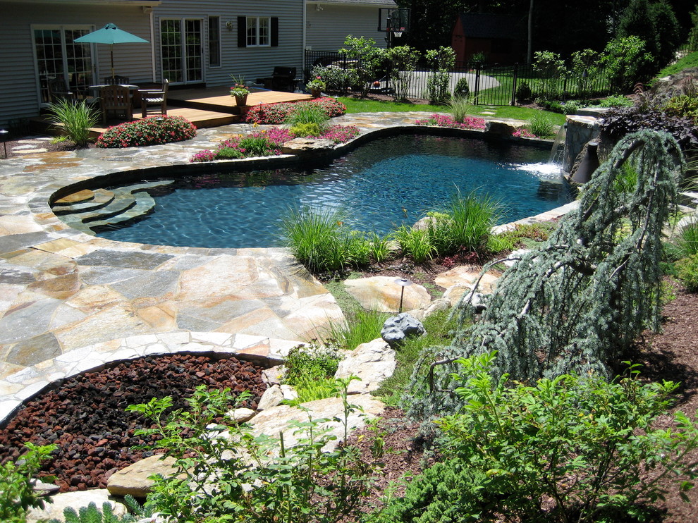Immagine di una piscina naturale classica personalizzata di medie dimensioni e dietro casa con fontane e pavimentazioni in pietra naturale