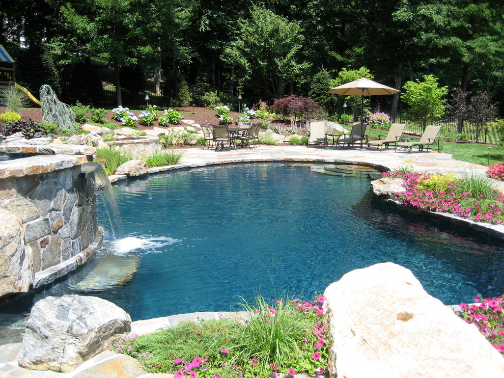 Ejemplo de piscina con fuente tradicional de tamaño medio a medida en patio trasero con adoquines de piedra natural