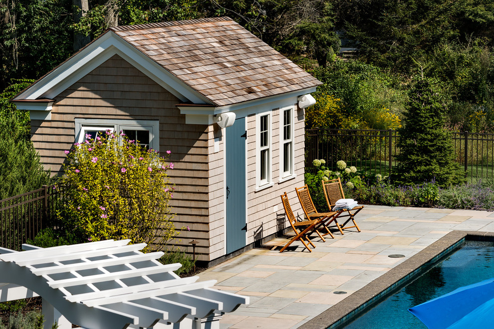 Modelo de casa de la piscina y piscina alargada costera de tamaño medio rectangular en patio trasero con adoquines de piedra natural