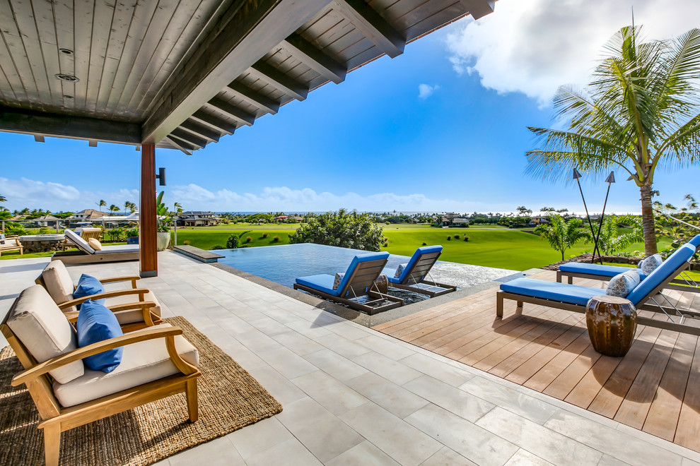 Example of a large island style backyard tile and rectangular infinity hot tub design in Hawaii