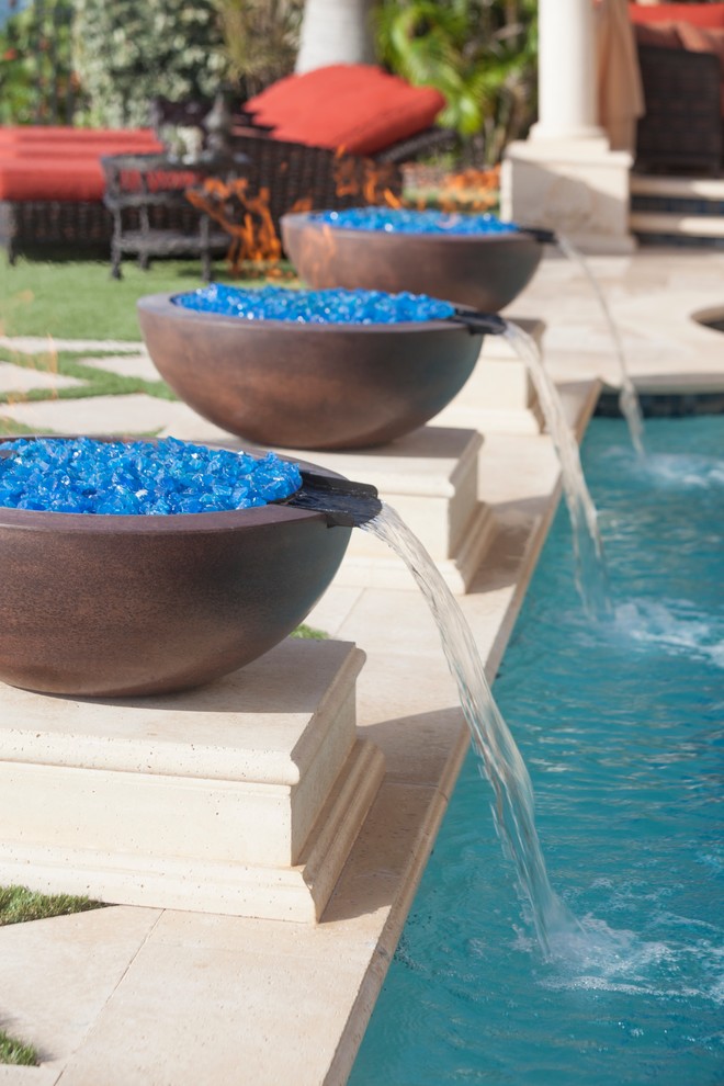 Ispirazione per una piccola piscina mediterranea rettangolare dietro casa con fontane e pavimentazioni in pietra naturale