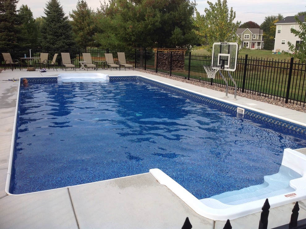 Foto de piscina natural de tamaño medio rectangular en patio trasero con losas de hormigón