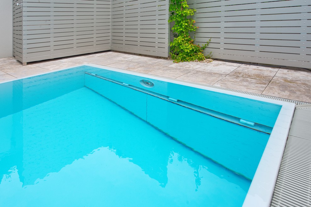 Cette image montre une grande piscine hors-sol et arrière minimaliste rectangle avec des pavés en pierre naturelle.